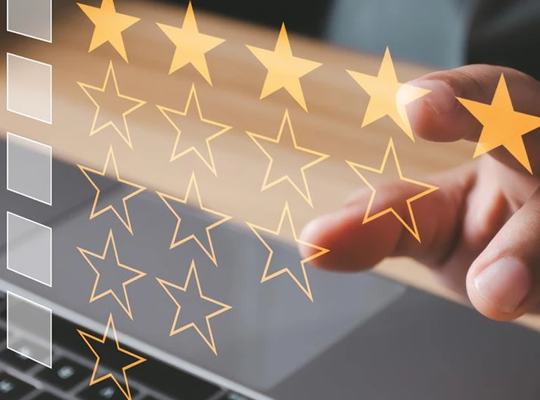 Hand interacting with a laptop keyboard alongside digital orange star rating icons.
