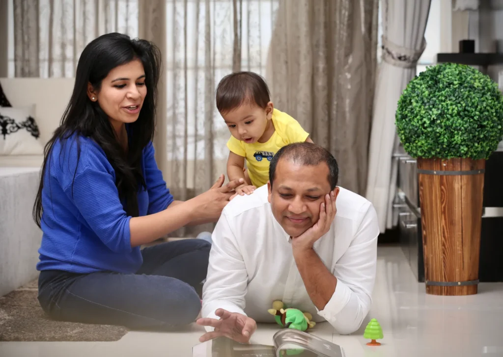 South Asian family with mother, father, and child interacting in living room with toys.