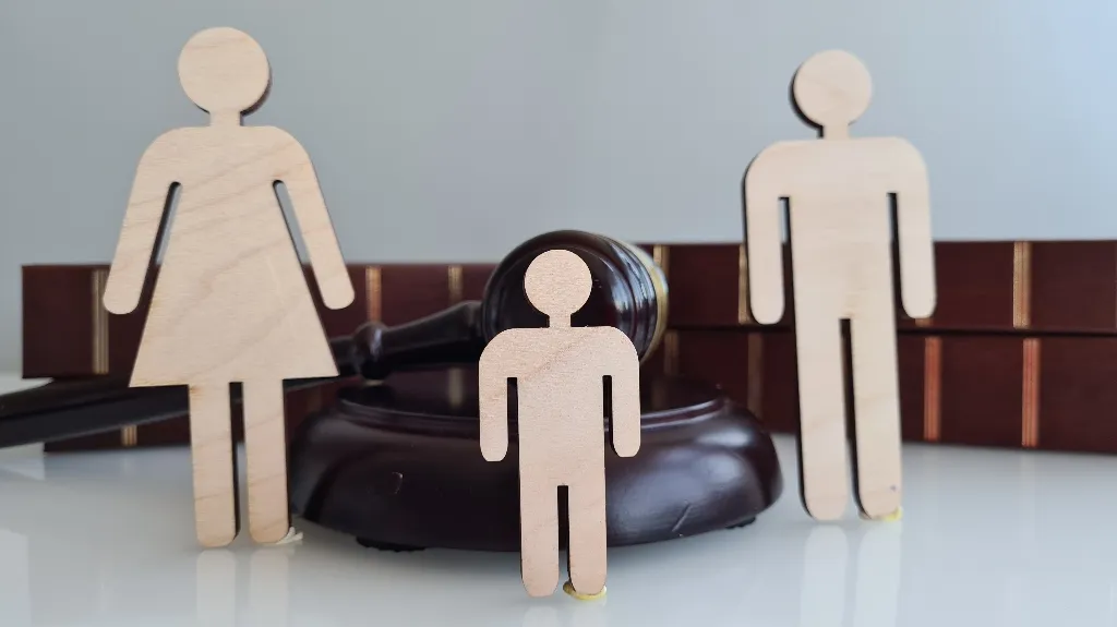 Wooden cutouts of a family with a judge's gavel and law books in the background.